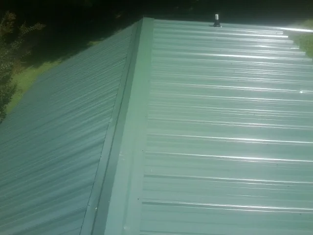 New green metal panels meeting at the ridge of a roof — Flat Roof Repair work by our crew in North Myrtle Beach