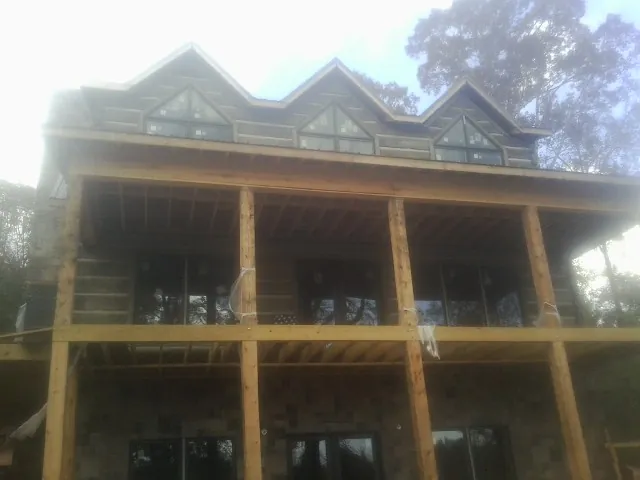 Dormers and porch framing on a large log home under construction — Roof Coating work by our crew in North Myrtle Beach