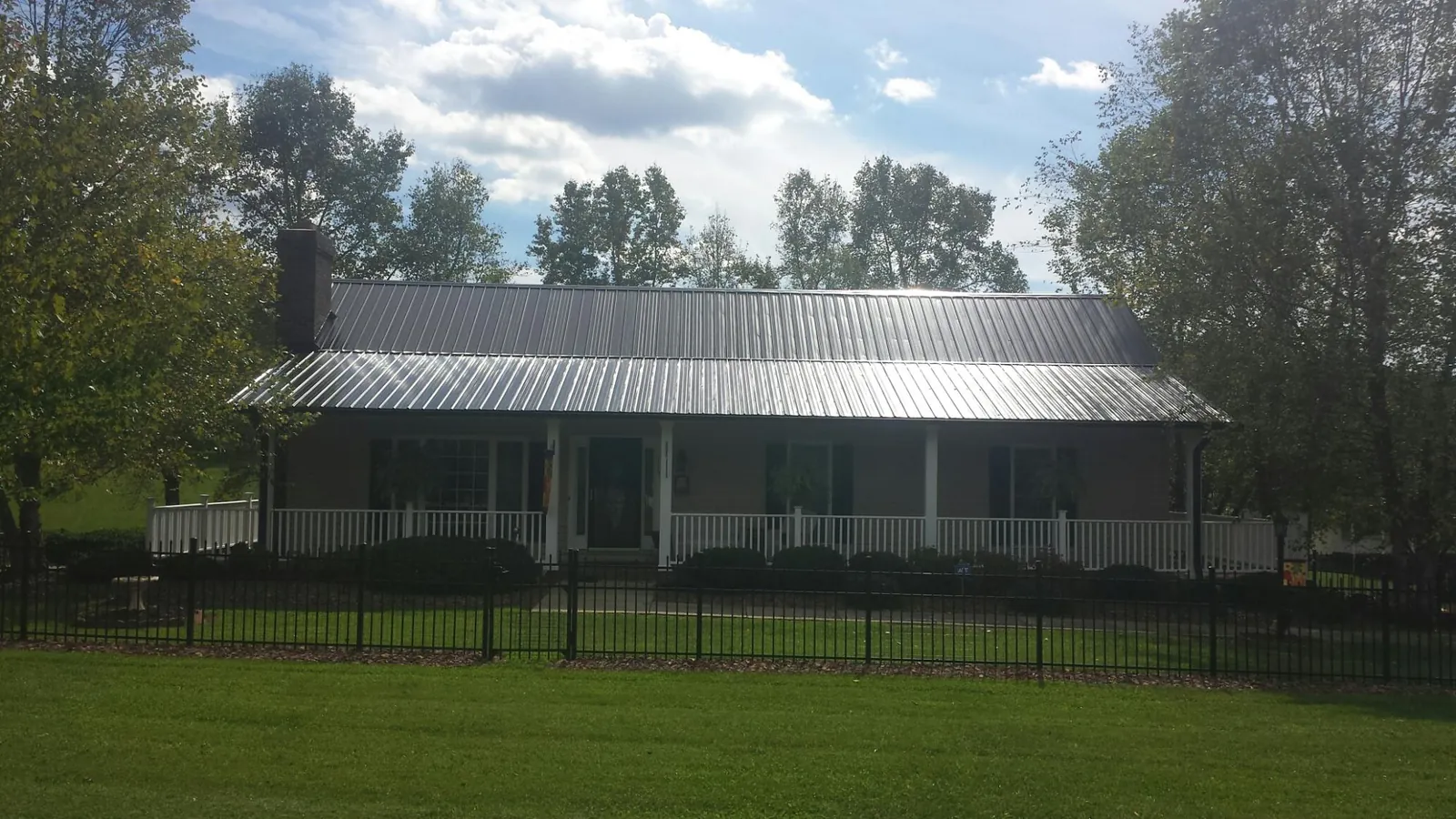 Gray metal roof on a brick ranch with a full width front porch — Gutter Guard Installation work by our crew in North Myrtle Beach