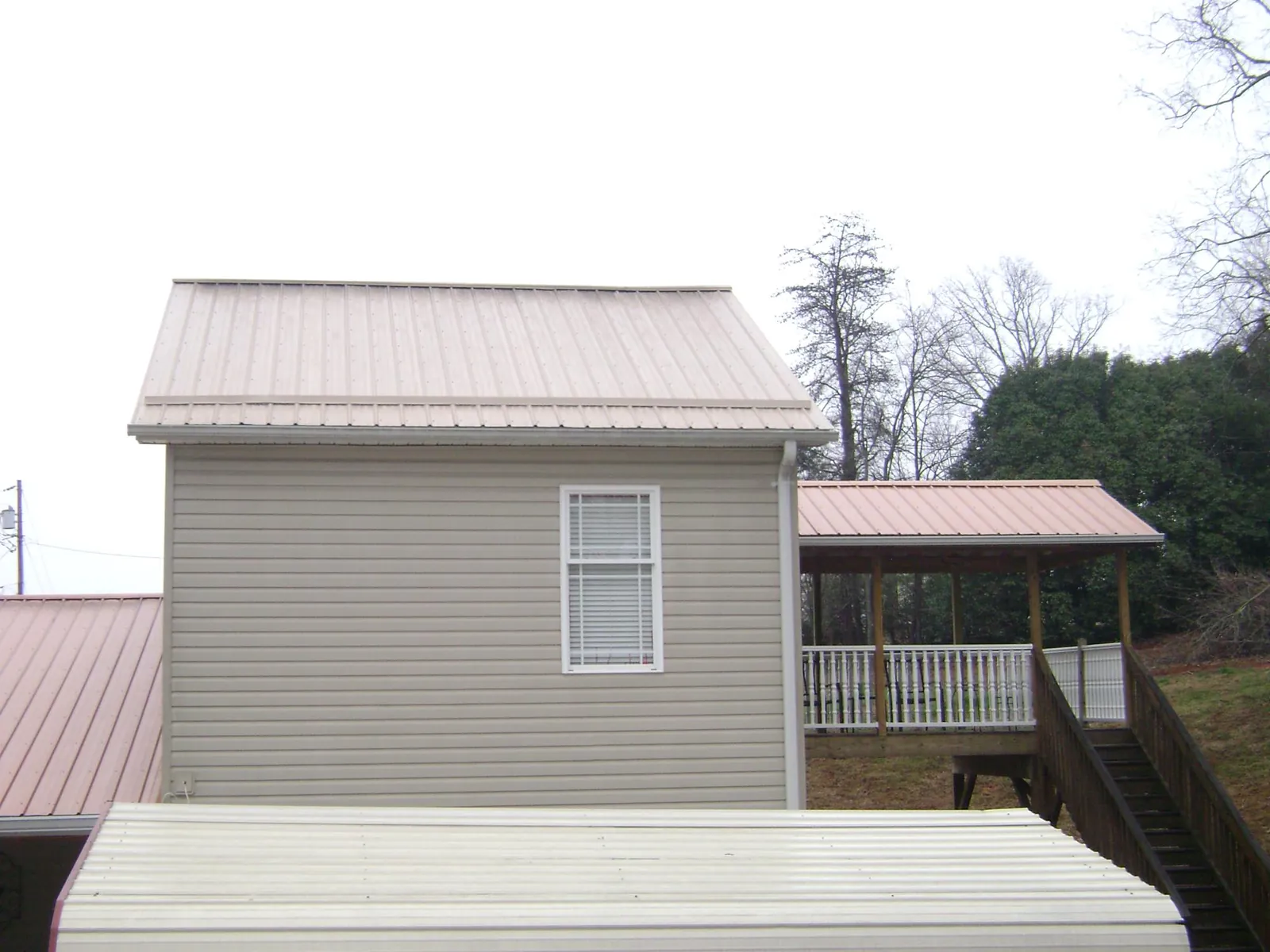 Tan metal roofs on a two story addition and attached porch, from a Roof Replacement job in North Myrtle Beach