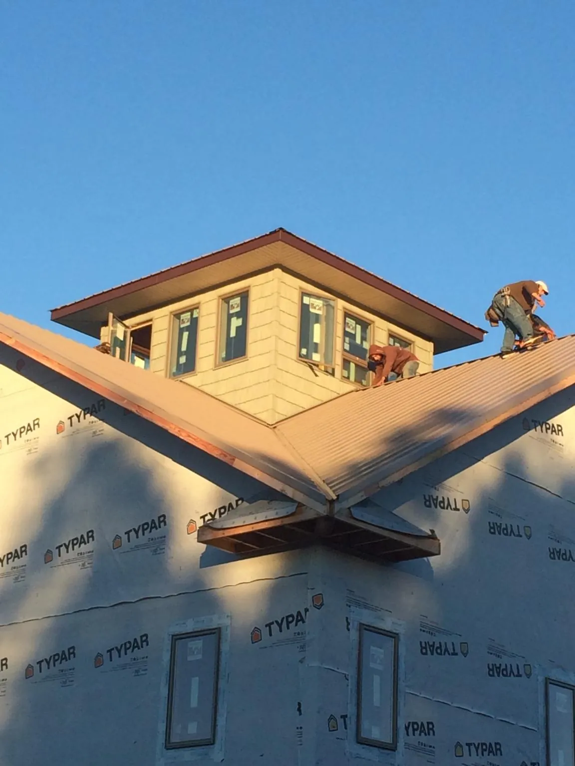 Roofers working around a rooftop cupola on a new metal roof at sunset — Roof Waterproofing in North Myrtle Beach by Roofing Brothers